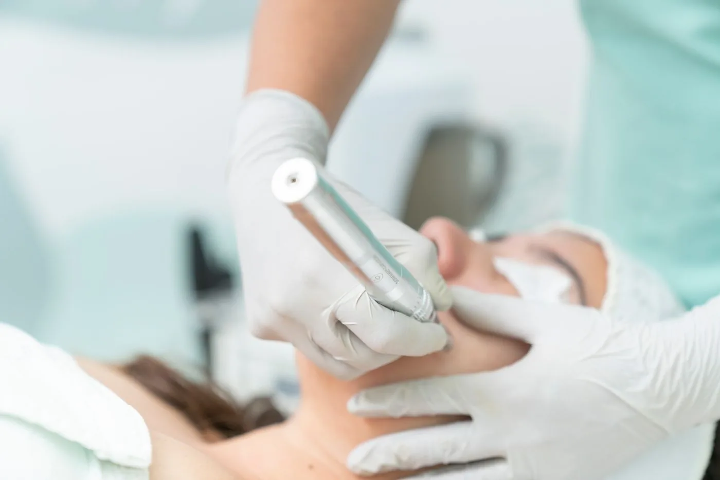 Profesional con guantes aplicando un dispositivo tipo pluma sobre la piel del rostro durante un tratamiento facial
